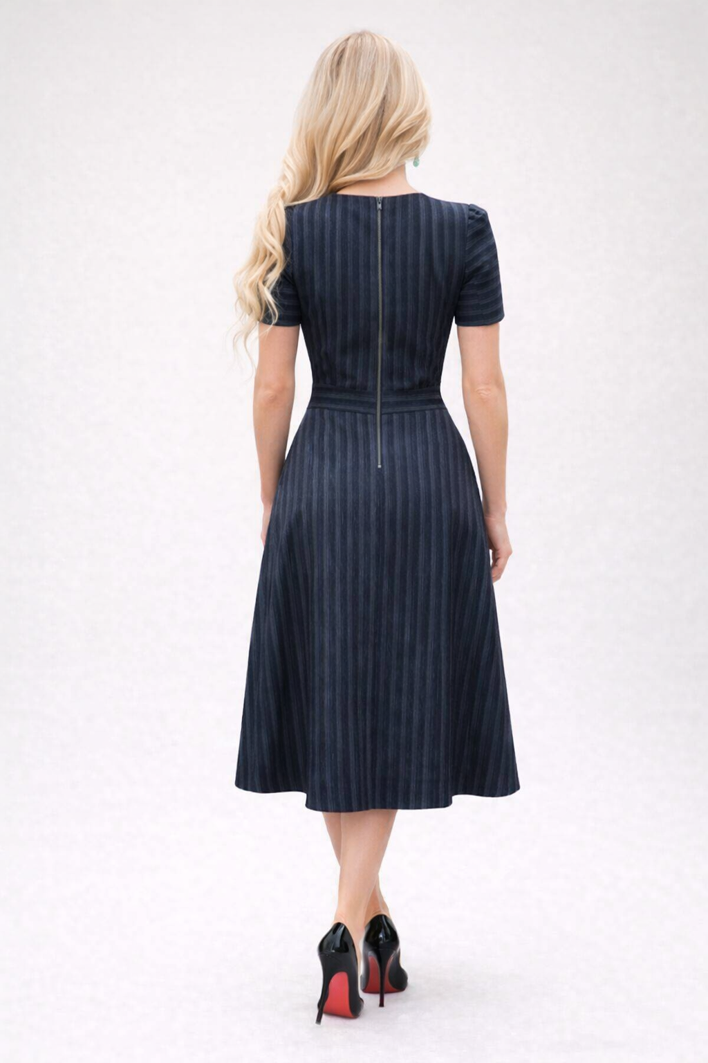 Woman wearing a navy pinstripe dress on a white background