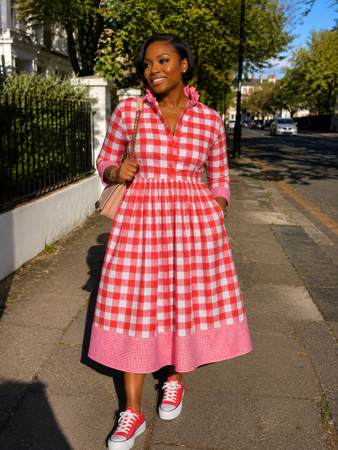 Woman in a red and white checkered dress walking on a sidewalk.