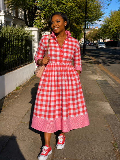 Woman in a red and white checkered dress walking on a sidewalk.