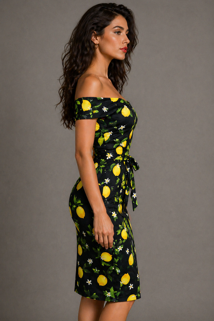Woman wearing a black dress with yellow lemon print against a gray background