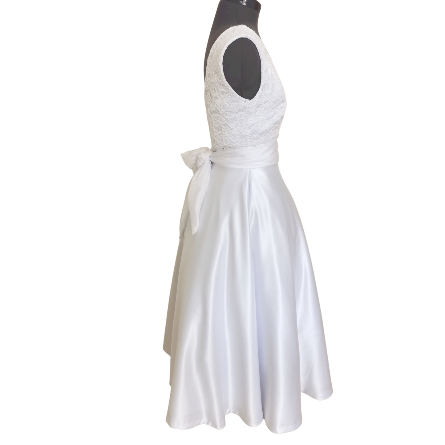 The Olivia Vintage Swing Dress is made with white cord lace on the upper bodice and duchess satin for the swing skirt; it is cut on the bias and swings freely based on the wearer's waist measurements. 